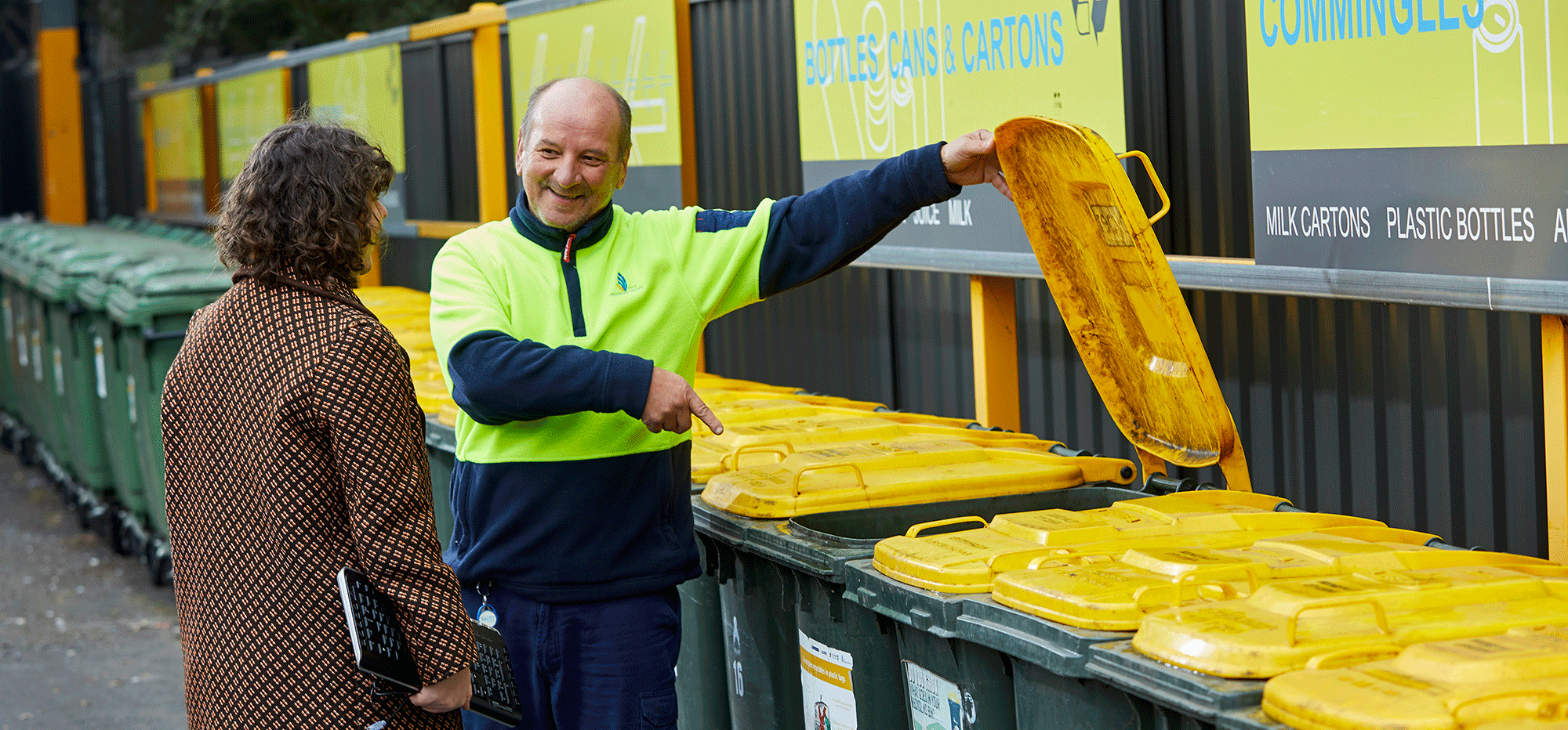 Yarra City Council staff showing to a person how to use recycling and waste bins.