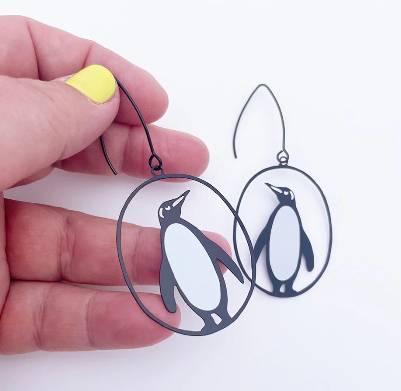 DENZ Midi Penguin Earrings, held by hand