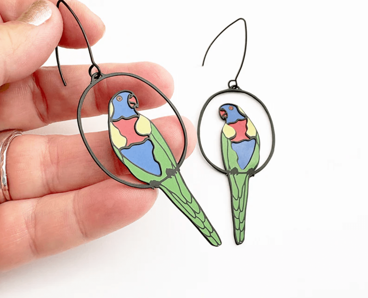 DENZ Rainbow Lorikeet earrings in Black/Rainbow, held by hand