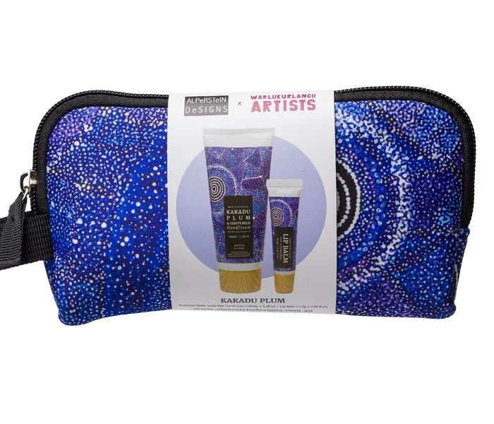 Alperstein Designs x Warlukurlangu Artists Kakadu Plum gift set featuring a cosmetic pouch, hand cream, and lip balm in a vibrant blue dot-art pattern, wrapped with a branded paper sleeve