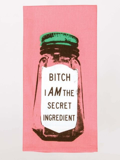 A pink folded Blue Q tea towel featuring a vintage spice jar graphic with a green cap and a white label reading "BITCH I AM THE SECRET INGREDIENT".