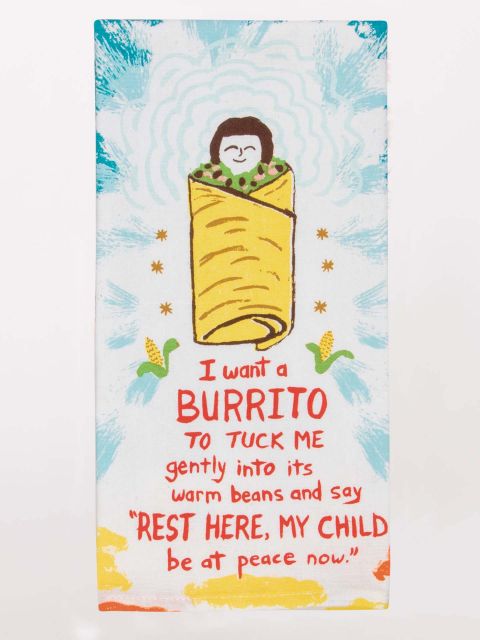 A white folded Blue Q tea towel illustrated with a smiling face tucked into a giant burrito surrounded by light bursts, with red text reading "I want a BURRITO to TUCK ME gently into its warm beans."