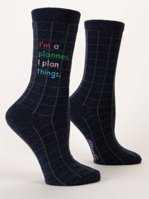 A pair of dark navy blue Blue Q crew socks with a grey grid pattern and colorful text reading "I'm a planner. I plan things."