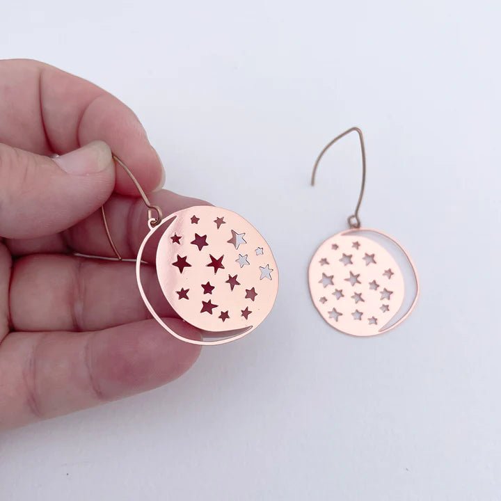 DENZ Mini Moonstars in Rose Gold earrings, held by hand