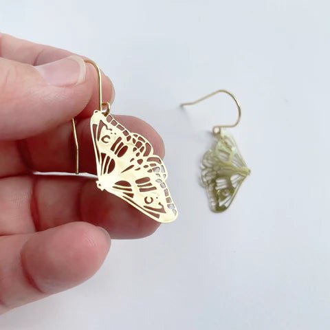 DENZ Mini Moth dangles in gold, held by hand