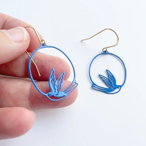 DENZ Mini Swallow dangles in blue, held by hand