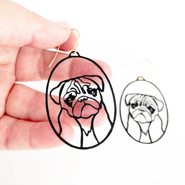 DENZ Pug Dangles in Black earrings, held by hand