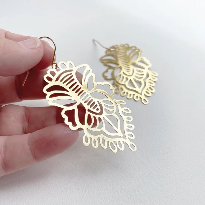 DENZ Rhapsody dangles in gold, held by hand