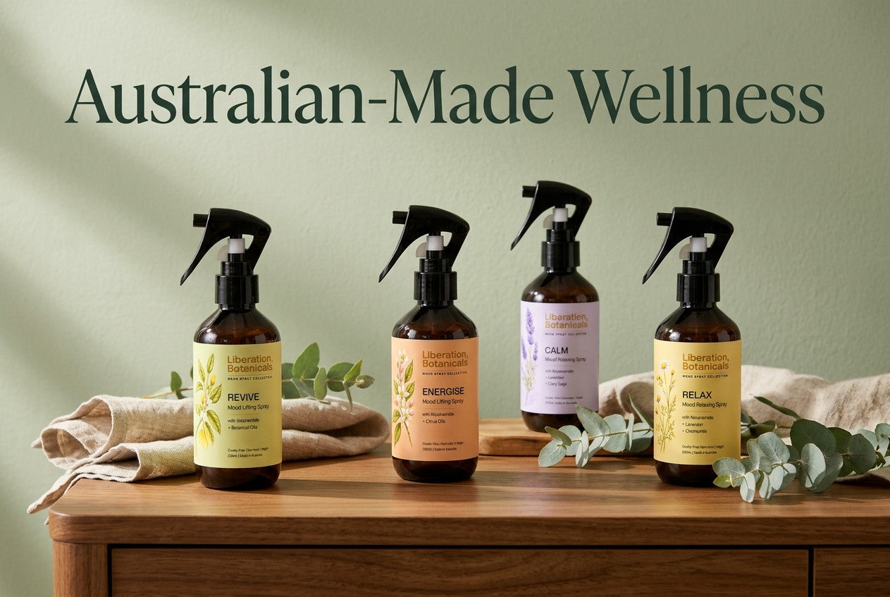 Four Liberation Botanicals sprays on a sunlit wooden console with eucalyptus foliage and the heading “Australian-Made Wellness”.