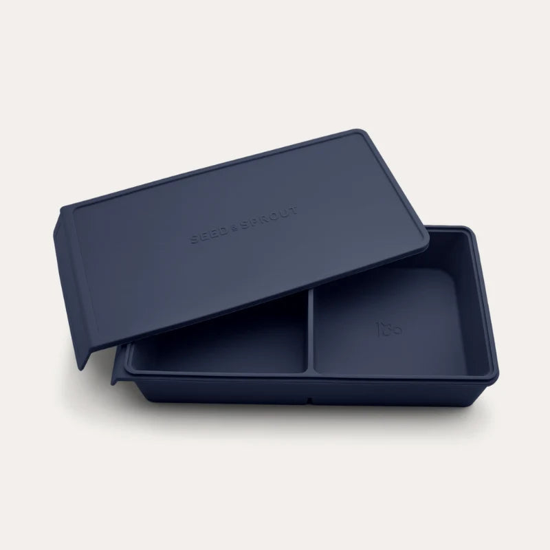 An open Seed & Sprout 2 Portion Blueberry Silicone Freezer Tray with two partitioned sections and its matching embossed lid resting partially on top.
