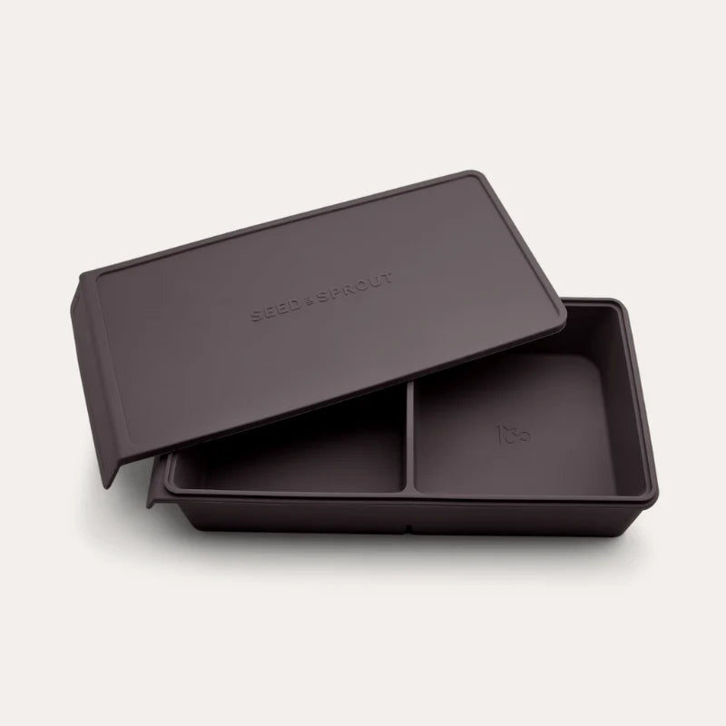 An open Seed & Sprout 2 Portion Macadamia Silicone Freezer Tray with two partitioned sections and its matching embossed lid resting partially on top.