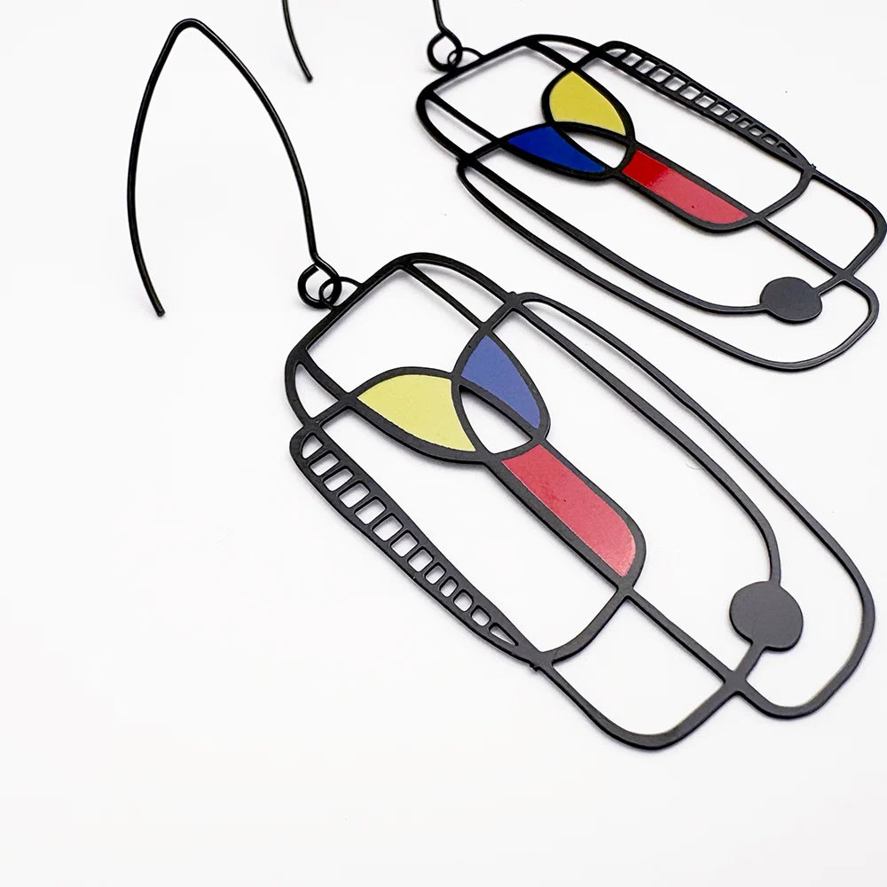 A pair of DENZ Art School Drop Out Earrings in Primary with abstract stained-glass style panels in yellow, blue, and red, shown on a plain white background.