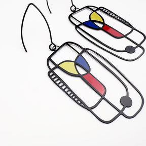 A pair of DENZ Art School Drop Out Earrings in Primary with abstract stained-glass style panels in yellow, blue, and red, shown on a plain white background.
