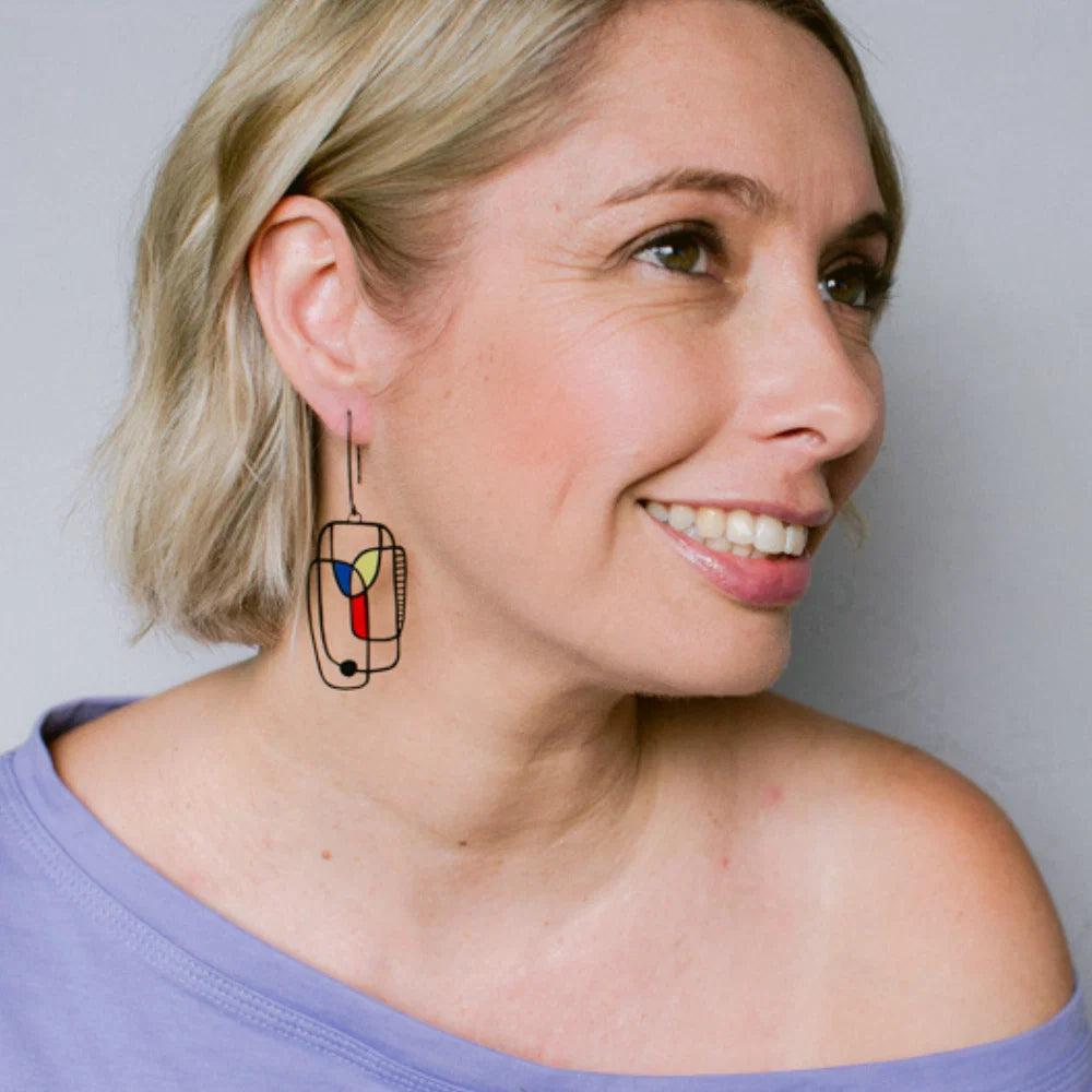 Woman wearing DENZ Art School Drop Out Earrings in Primary against a plain background