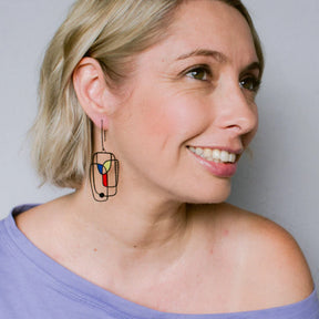 Woman wearing DENZ Art School Drop Out Earrings in Primary against a plain background