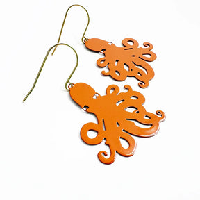 A pair of DENZ orange octopus-shaped dangle earrings with gold-tone fishhook wires, displayed on a clean white background.