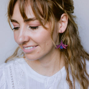 Woman wearing colorful DENZ Fuchsia Flower Earrings with a neutral background