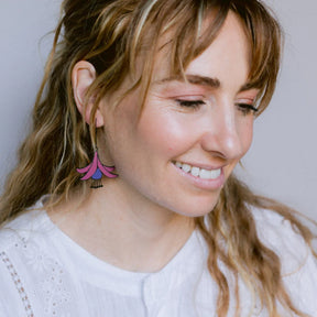 Woman wearing a colorful DENZ Fuchsia Flower Earrings with a plain background