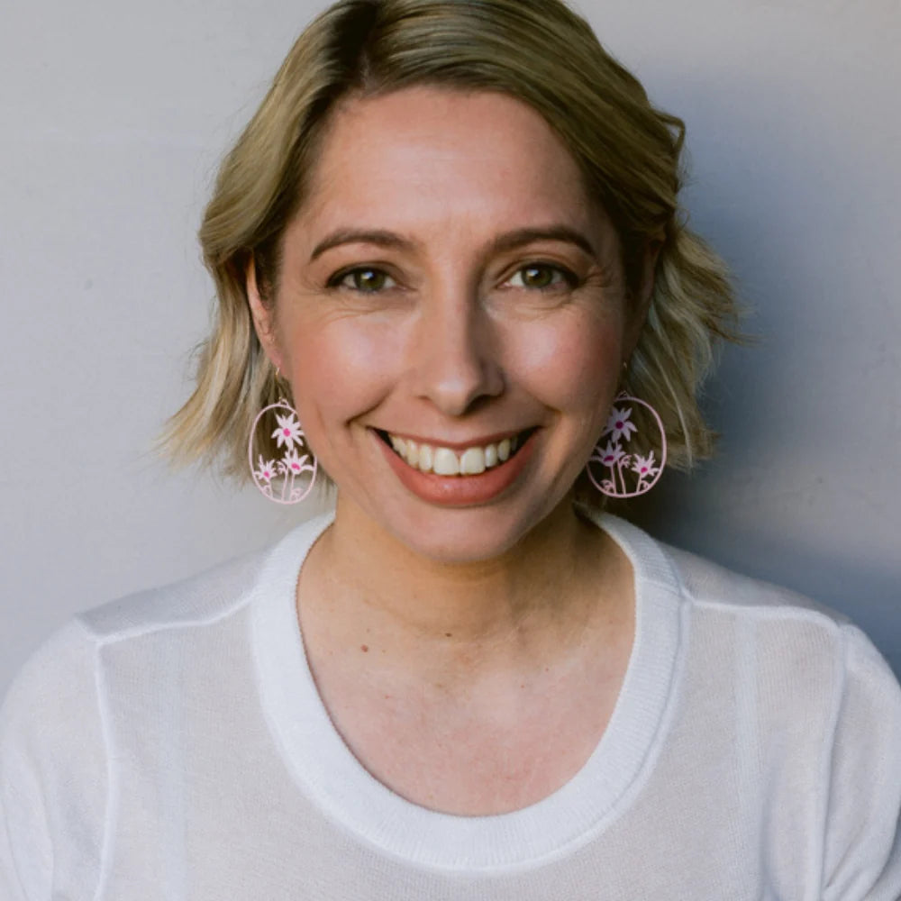 Woman wearing a white shirt with DENZ Flannel Flower earrings against a plain background
