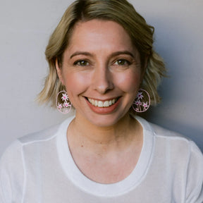 Woman wearing a white shirt with DENZ Flannel Flower earrings against a plain background