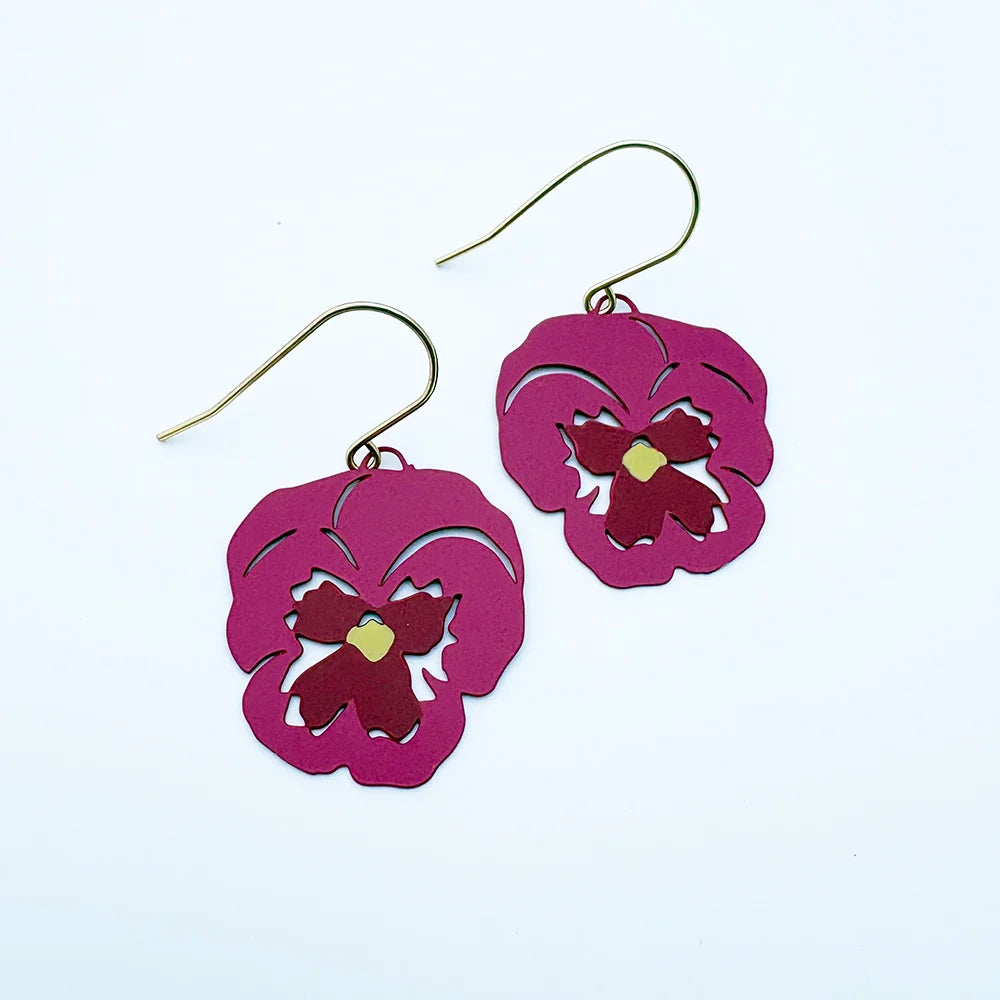 A pair of DENZ dangling earrings with magenta-pink flower-shaped cutouts and gold-tone fishhook wires, shown on a plain white background.