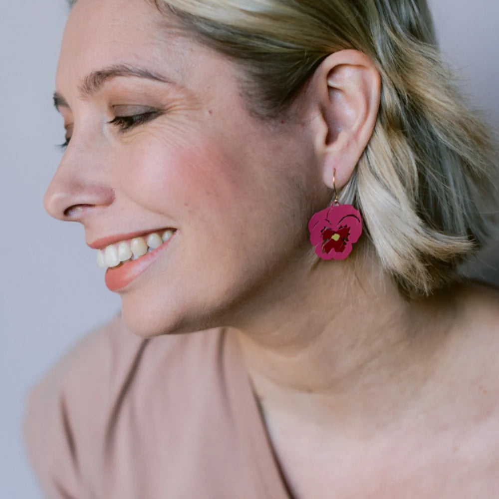 Woman wearing DENZ Pansy Flower  earrings with a neutral background