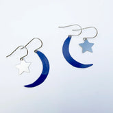 A pair of DENZ Moon & Star Stacker silver-toned dangle earrings featuring glossy dark blue crescent moon charms and matte light blue star charms, displayed on a clean white background.