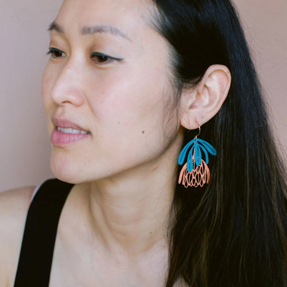 Woman wearing colorful DENZ Protea Flower dangle earrings with a neutral background