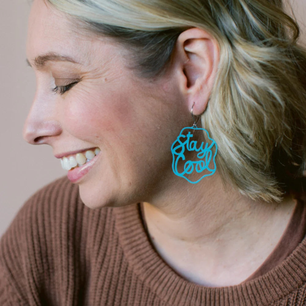 Woman wearing a DENZ mint blue 'Stay Cool' earring with a neutral background