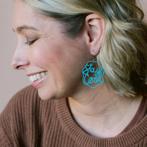 Woman wearing a DENZ mint blue 'Stay Cool' earring with a neutral background