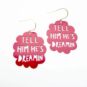 A pair of DENZ pink cloud-shaped dangle earrings with gold fishhook wires. The front of each earring features a scalloped red gradient overlay containing the white text 'TELL HIM HE'S DREAMIN'.