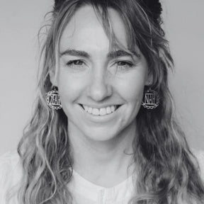 Black and white photo of a person with wavy hair wearing DENZ "Yeah Nah" earrings.