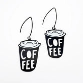 A pair of DENZ Coffee Cup  earrings with the word 'COFFEE' printed on them, shown against a plain white background.