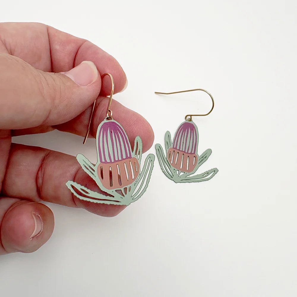 Denz Banksia Flower Earrings in Sage, Burnt Orange & Wine, held by hand