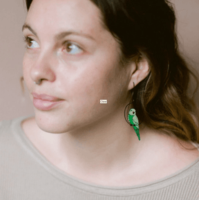 Side profile of a woman wearing the DENZ Budgies Earrings in Black/Green/Yellow 