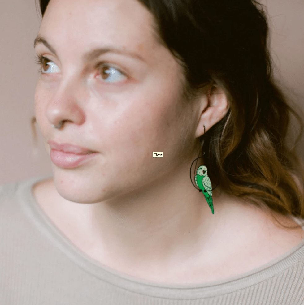 Side profile of a woman wearing the DENZ Budgies Earrings in Black/Green/Yellow 