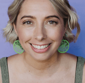 Woman wearing the DENZ Citrus Slice earrings in lime green