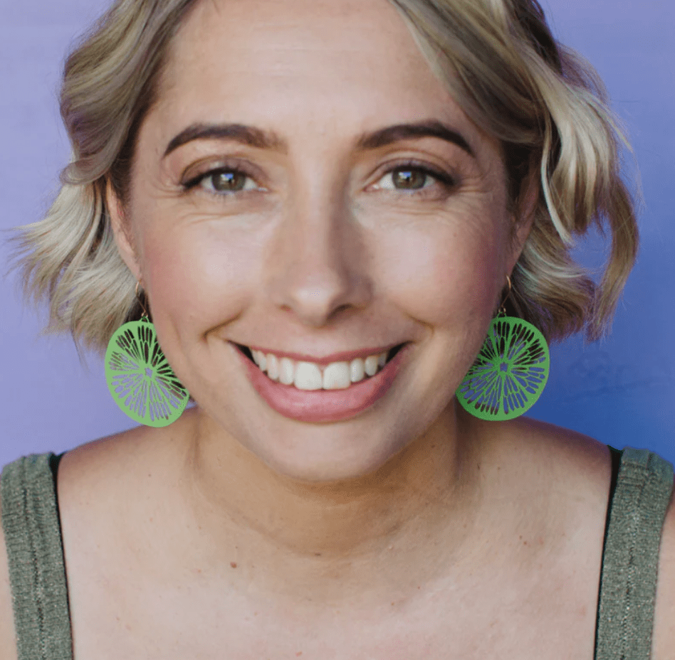 Woman wearing the DENZ Citrus Slice earrings in lime green