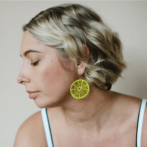 Woman wearing the DENZ Citrus Slice earrings in lemon