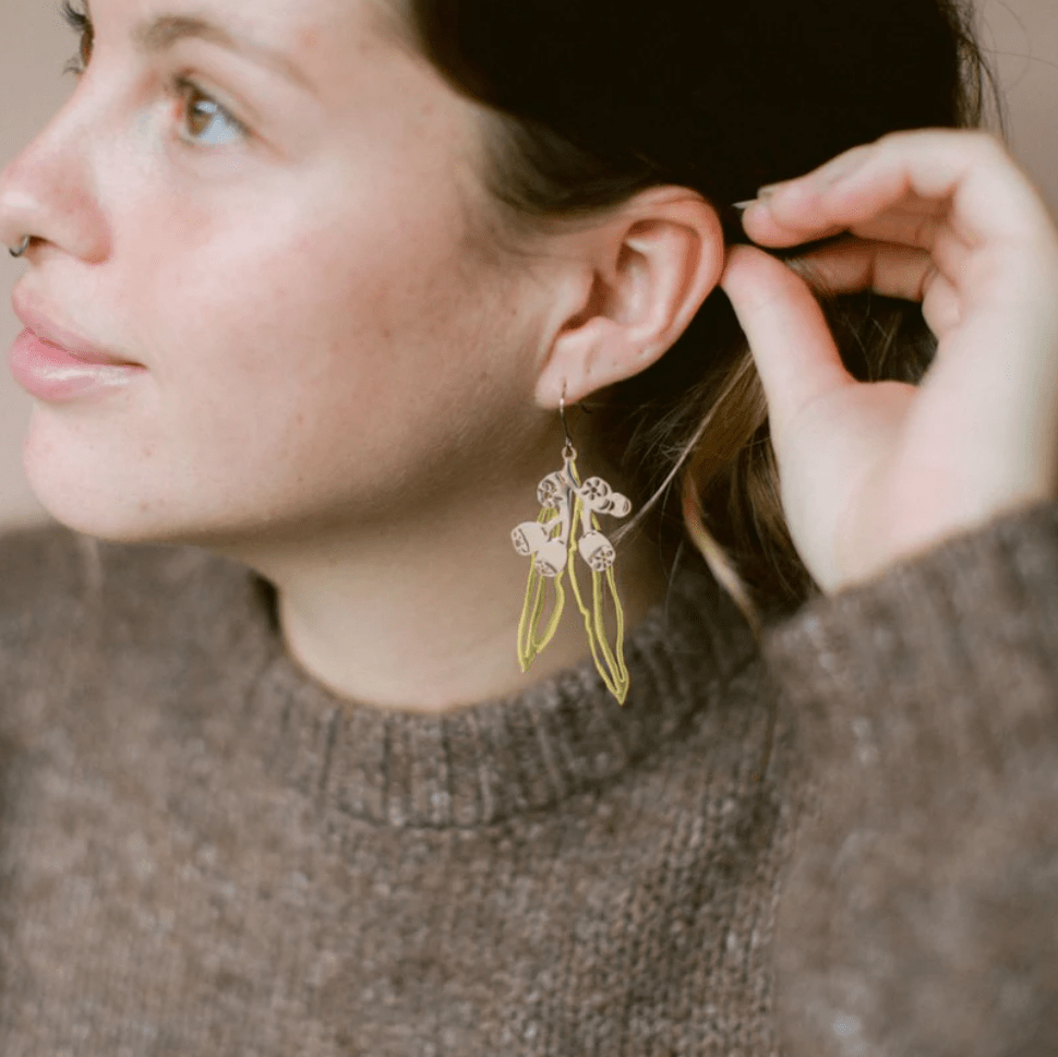 Woman is wearing the DENZ Gumnut & Leaf dangle earrings in Gold/Silver 