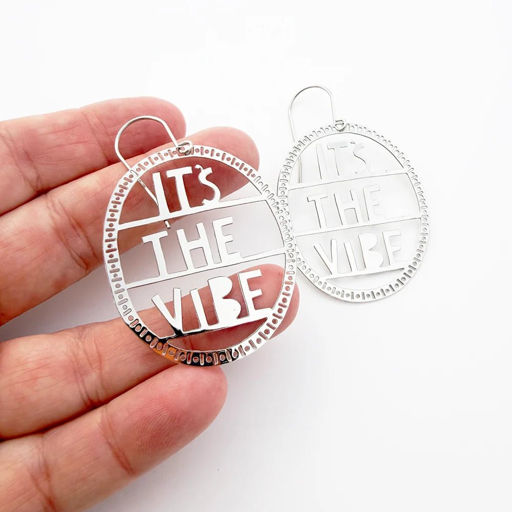 DENZ It's The Vibe Earrings in Silver, held by hand
