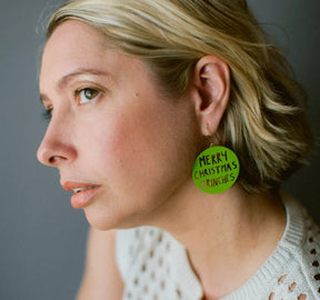 Side profile of a woman wearing Denz Merry Christmas Grinches Earrings in Grinch Green 
