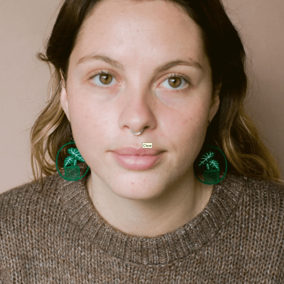 Woman wearing the DENZ Midi Alocasia plant earrings in Green/White 