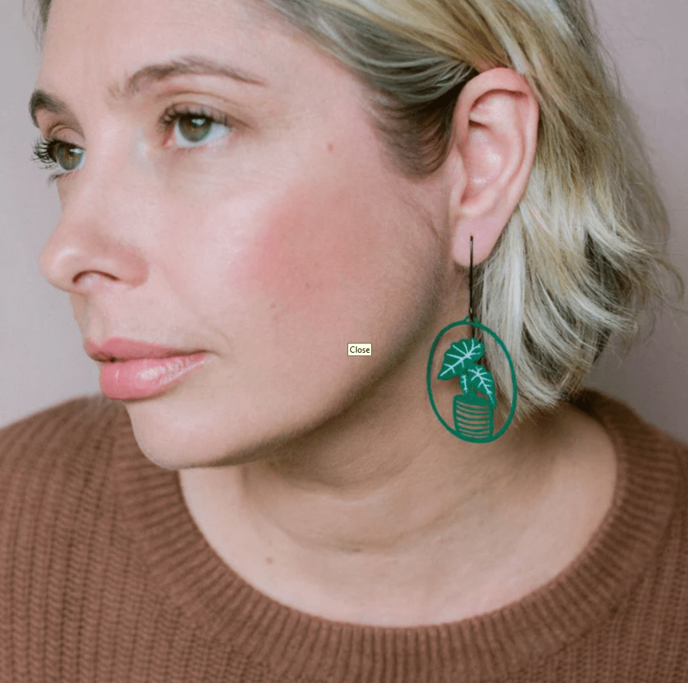 Side profile of  woman wearing DENZ Midi Alocasia plant earrings in Green/White 
