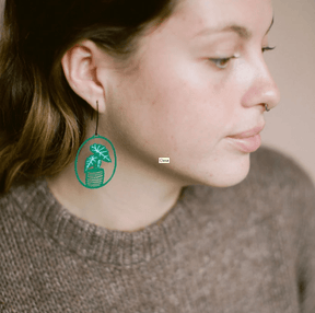 Close-up profile of a woman DENZ Midi Alocasia plant earrings in Green/White 