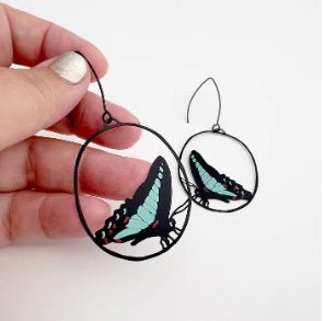 Denz Midi Butterfly Earrings in Blue Triangle, held by hand