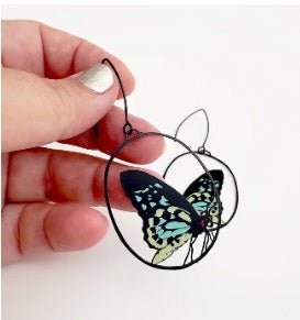 Denz Midi Butterfly Earrings in Cairns Birdwing, held by hand