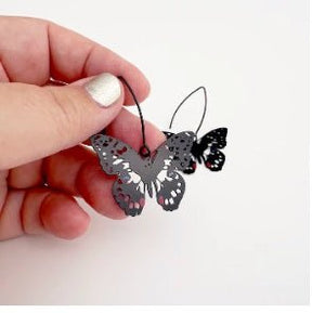 Denz Midi Butterfly Earrings in Chequered Swallowtail, held by hand