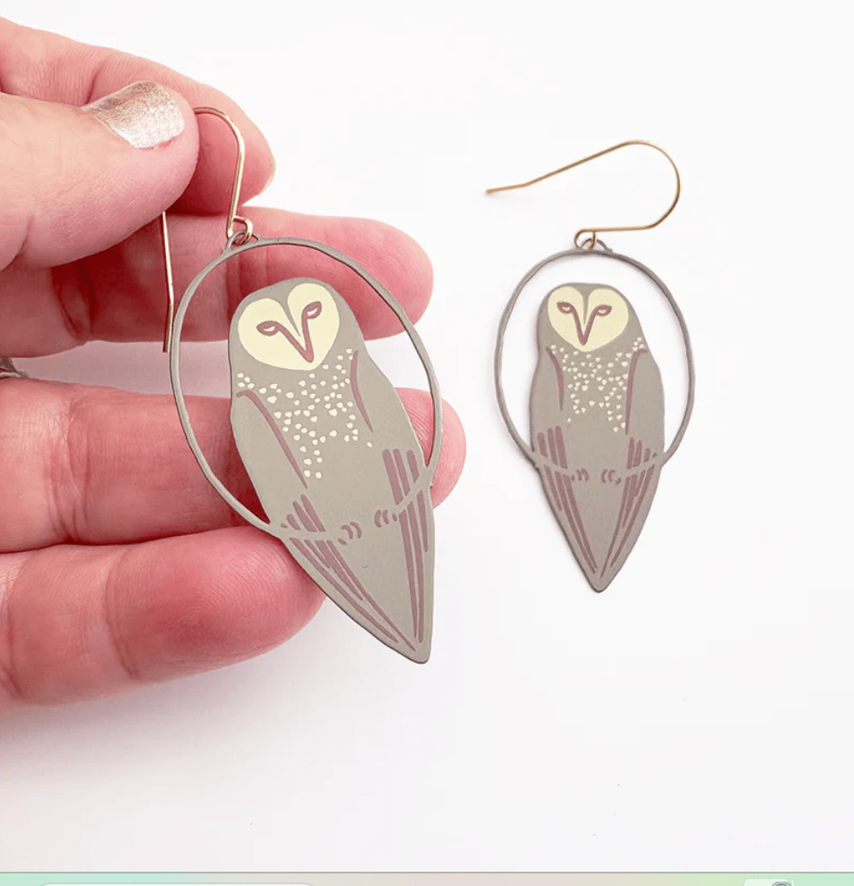 DENZ Midi Masked Owl earrings in brown, held by hand