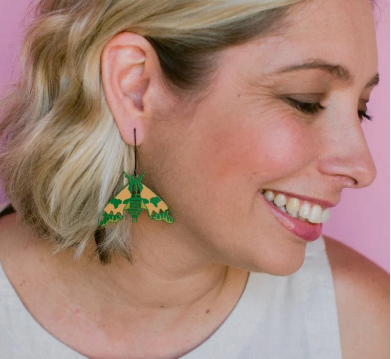Side profile of a woman smiling wearing Denz Midi Moth Earrings in Lime Hawk 